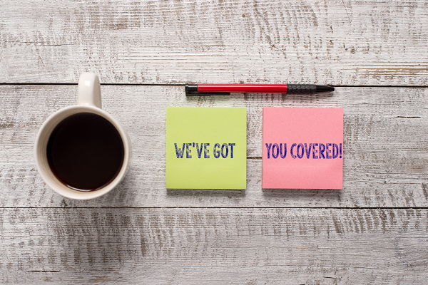 Coffee cup, green and pink sticky notes with motivational phrases, and a pen on a wooden surface, symbolizing support in direct mail fundraising for nonprofits and agencies.